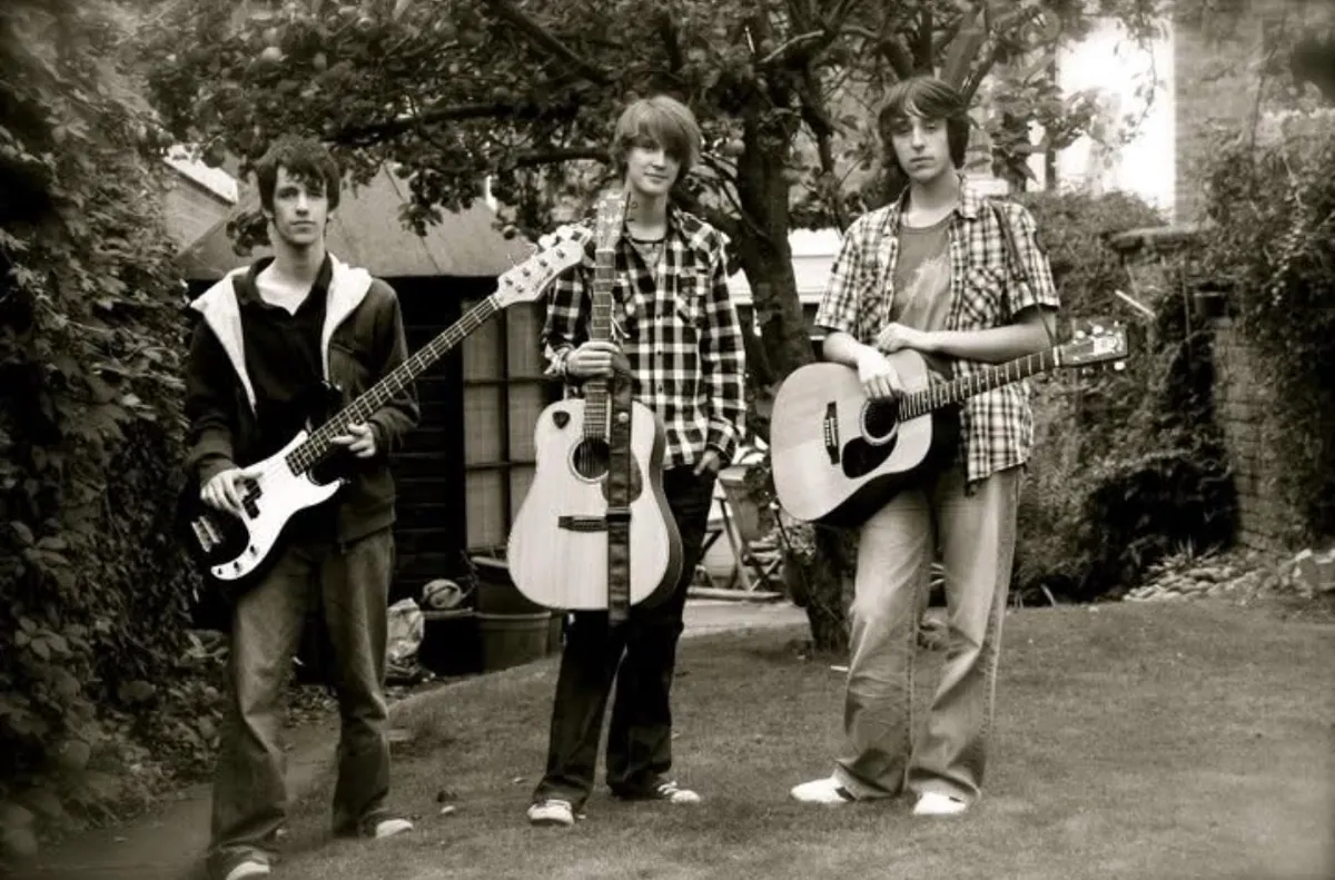 Jamie, Fergus and Antony with their instruments in a black-and-white photo from their school days