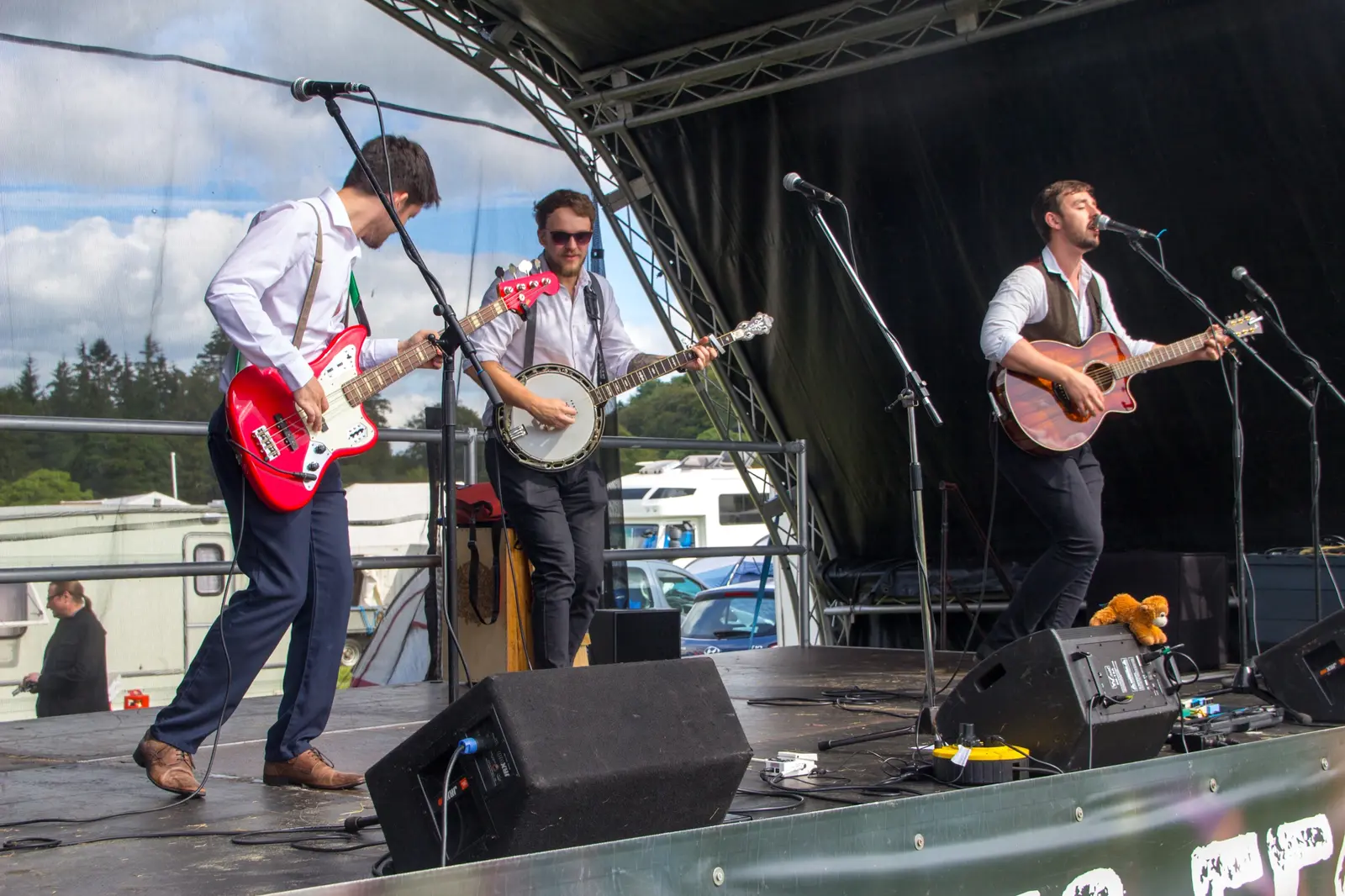 Jamie on bass, Fergus on banjo and Antony singing with guitar on an outdoor festival stage